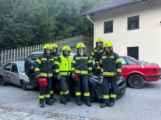 Feuerwehrleute in Uniform mit Helm und Warnweste vor verunfallten Autos